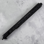 Long black rifle handguard with vented slots lying diagonally on a gray concrete surface. - 10.5″ .300 Blackout AR-15 Upper – Suppressor-Ready | 15″ M-LOK Handguard & Mock Suppressor - Mid State Firearms , Mid State Firearms
