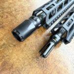 Close-up of a black rifle handguard with a muzzle brake on a brown workshop surface. - OTX CASTLE BLAST SHIELD Concussion Device - Mid State Firearms , Mid State Firearms