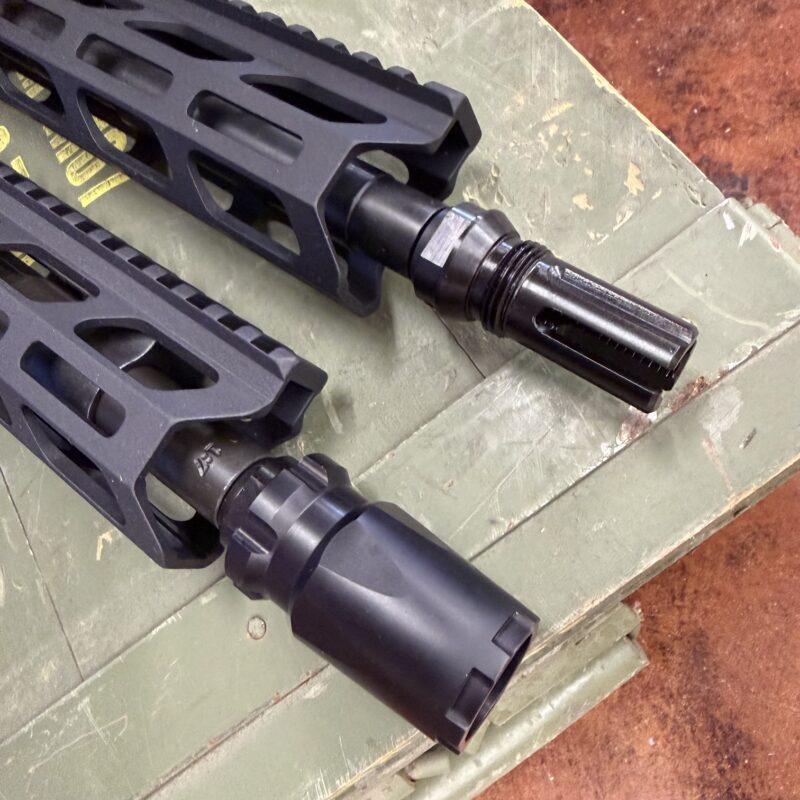 Close-up of a black rifle handguard with modular rails and a threaded barrel ending in a slotted muzzle device on a green surface. - OTX CASTLE BLAST SHIELD Concussion Device - Mid State Firearms , Mid State Firearms
